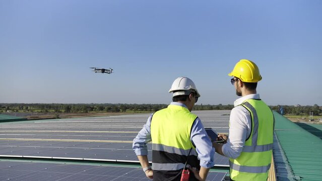 Professional engineer using drone and digital tablet maintaining solar cell panels together on building rooftop. Technician working on ecological solar farm. Renewable clean energy technology concept