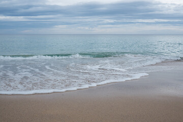 Fototapeta na wymiar Australian south coast beach. Water and sea foam on sand.