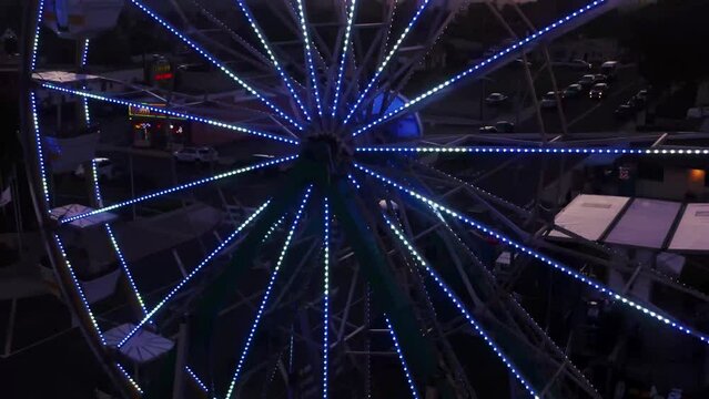 Outdoor carnival event with ferris wheel turning and other amusement and thrill rides moving on main street fair grounds.  Sunset event, shows, and party in a small country town. Tickets for passenger
