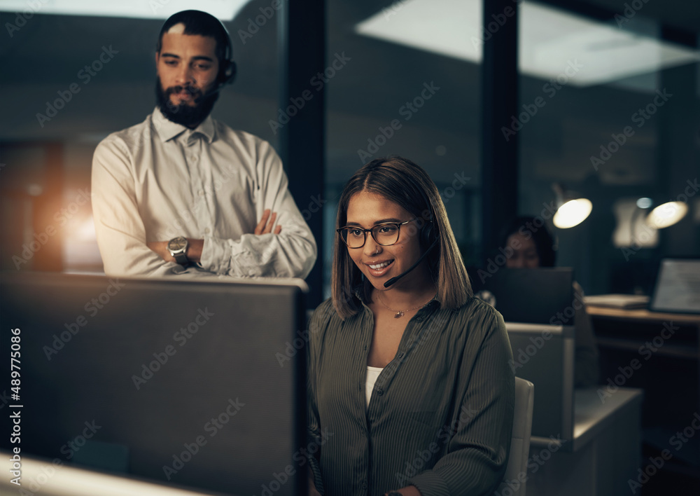 Poster The problem solvers are at it again. Shot of two call centre agents working together in an office at night.