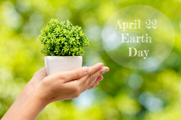 Woman hands in jardiniere on a natural background and text  April 22 Earth Day .Concept Earth Day