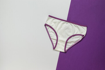 White panties with a purple border on a white and purple background. Women's underwear.