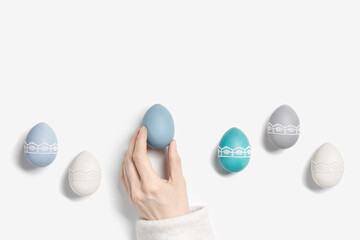 Painted Easter eggs pastel colored and handmade decorated on white background. Female hand holding chicken egg with tape lace decor. Holiday food, symbol easter, still life aesthetic flat lay