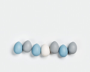 Dyed Easter eggs pastel colors blue, gray in row on white background. Happy Easter holiday, celebration food concept, chicken egg monochrome color. Top view table