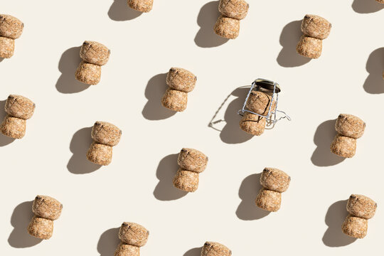 Pattern with champagne cork on beige background with hard light and shadow at sunlight. Trend layout with bottle cap from sparkling wine and metal wire muselet, repeat pattern top view