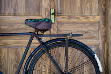 Old fashioned vintage bicycle against wooden door close up shot.
