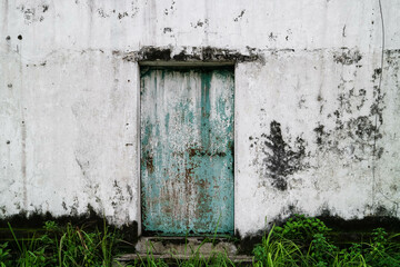 Closed old rusty metal iron entrance door with grunge concrete wall.