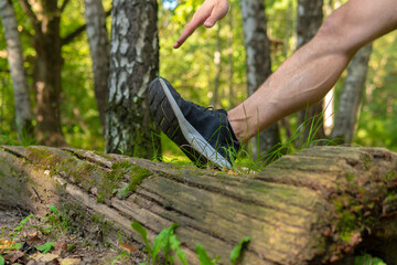 A young enduring athletic athlete is doing stretching in the forest outdoors, around the forest,...