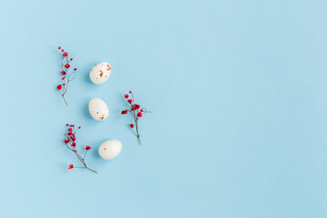 Easter minimal composition with eggs and flowers on the blue background. Easter concept. Copy space, flat lay.