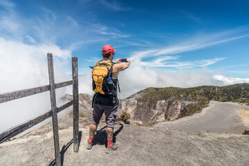 hiker with backpack taking a photo of the landscape in Irazu Volcano National Park in Costa Rica