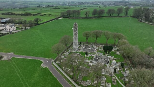 Monasterboice, County Louth, Ireland, January 2022. Drone gradually orbits the ruined Round Tower with surrounding monastic cemetery from the south side.