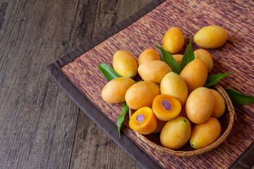 bunch of marian plum in a basket on wooden table with copy space