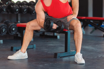 Athletic man trains with dumbbells in the gym. Close-up. Fitness and bodybuilding concept