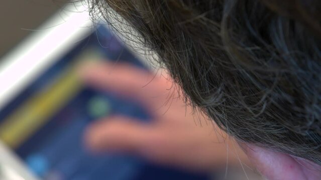 Male hands on an iPad tablet operating a smart home automation light system app. Focus pull head to iPad.