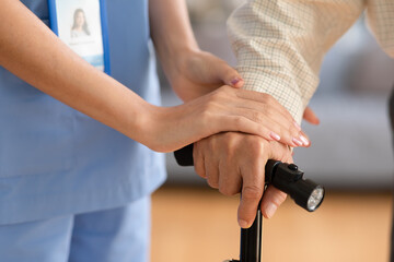 close up hand of doctor or nurse holding hand of elderly patient on cane or walking stick hope and...