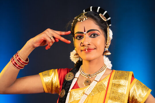 Close up shot of bharatanatyam dancer doing eye moments or drishti bheda by looking at camera - concept of indian culture, traditional classical dancer.