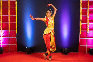 Full shot of Bharatnatyam dancer performing on stage - conept of professional artist, Indian traditional dance and culture