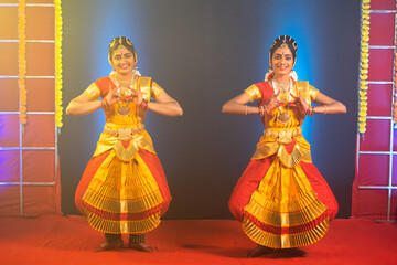 Traditional young bharathnatyam dancers performing on stage - concept of indian culture and professional classical dancers.