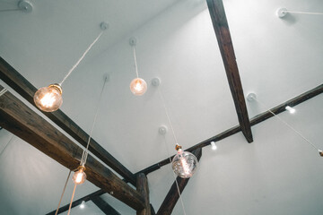 Modern loft style apartment with fancy vintagy style light bulbs hanging from the ceiling supported by wooden trusts.