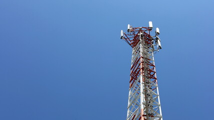 Obraz premium Cellular Base Station Tower. A base station equipped with 4G and 5G cellular wireless communication technology with a mobile phone with a clear sky background with copy space. Selective focus