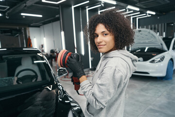 Auto detailer holding car buffer in her hands