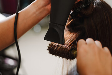 Naklejka premium Hair salon concept a male hairstylist using a comb to grab a lock of hair and using hair dryer for drying and straightening
