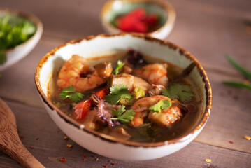 hot delicious asian seafood soup (shrimp, mussels, squid, shellfish) on a wooden background
