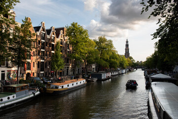 View of a canal, houseboats and apartment buildings on a sunny spring morning in Amsterdam.