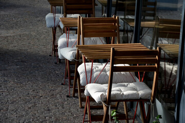 wooden chairs and tables in a cafe on a cobbled square in front of a cafe. everything is made of...