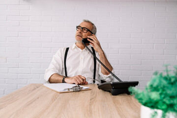 man in the office with a document to sign and talking on the phone