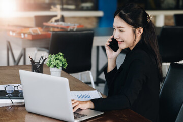 A female business woman is using the telephone to communicate with colleagues for financial planning and investment planning.