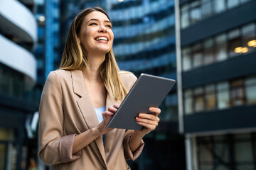Portrait of a successful business woman using digital tablet in front of modern business building