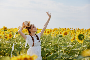 Naklejka na ściany i meble woman with pigtails looking in the sunflower field unaltered