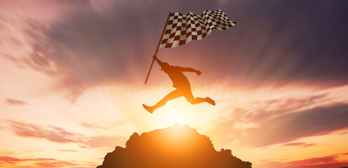 The concept of jumping over obstracles to success. Silhouette of a man holding aflag jumping on top of mountain