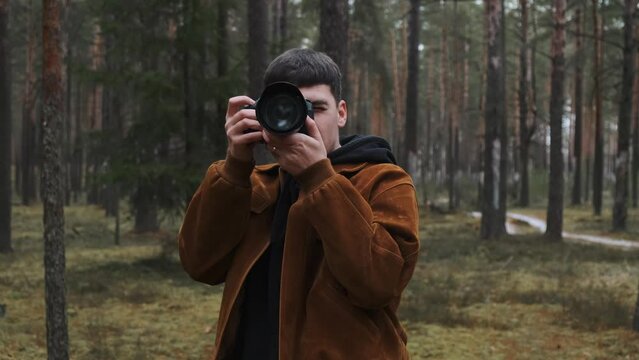 A photographer takes pictures in the woods, a young man takes pictures in the woods with his camera. Beautiful nature through the eyes of a photographer. . High quality 4k footage