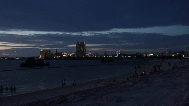 CHTAN-CHO, OKINAWA, JAPAN - JUNE 2021 : View of Araha beach (Ocean or sea) at night. Firework for cheering up the nation as it struggles with the Coronavirus (COVID-19) pandemic.