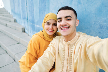Young couple taking selfie in front of blue wall