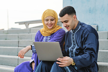 Young man using laptop sitting with woman on staircase