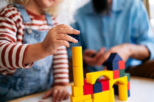 Boy Building House With Toy Blocks By Father At Home