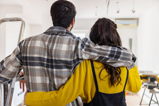 Man with arm around girlfriend looking at room being renovated