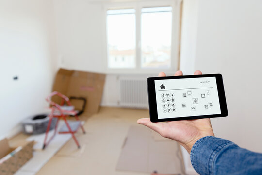 Young Man Using Tablet PC With IOT App At New Home