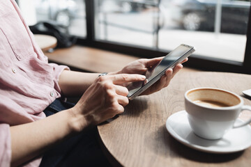 Young woman using smartphone at cafe. Student girl texting on mobile phone at coffee shop. Communication, home work or study, connection, mobile apps, technology, lifestyle concept