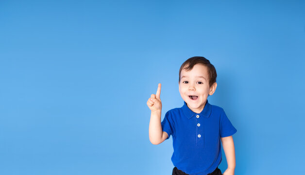 Portrait of a happy little boy on a blue background with thumbs up - The concept of childhood, growing up and achievements - front view, space for text