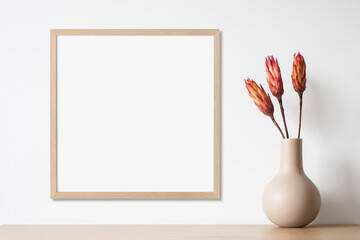 Blank picture frame mockup on white wall, template for square artwork. View of modern minimal style...