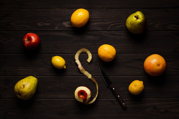 Naklejka na ściany i meble A variety of fruits on a wooden background, lemon, grapefruit, a peeled apple, pear, citrus, knife. Overhead shot.