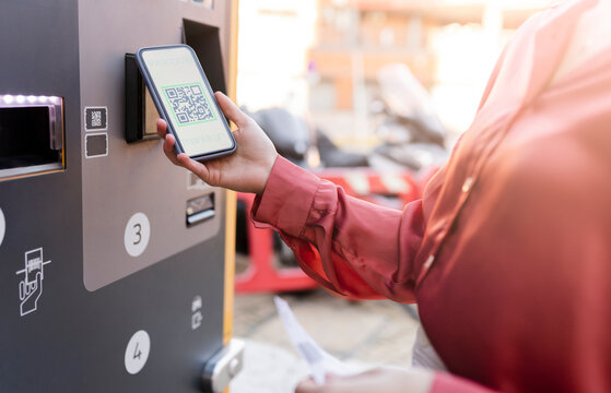 Woman scanning QR code on ticket machine at station