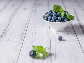 fresh blueberries in a white bowl served on white wooden table