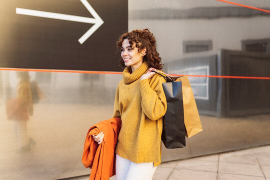 Young woman with shopping bags walking on footpath