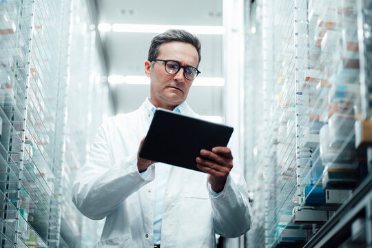 Pharmacist with tablet PC taking inventory in pharmacy