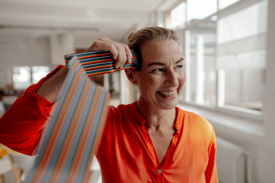Cheerful businesswoman touching computer cables on head in office